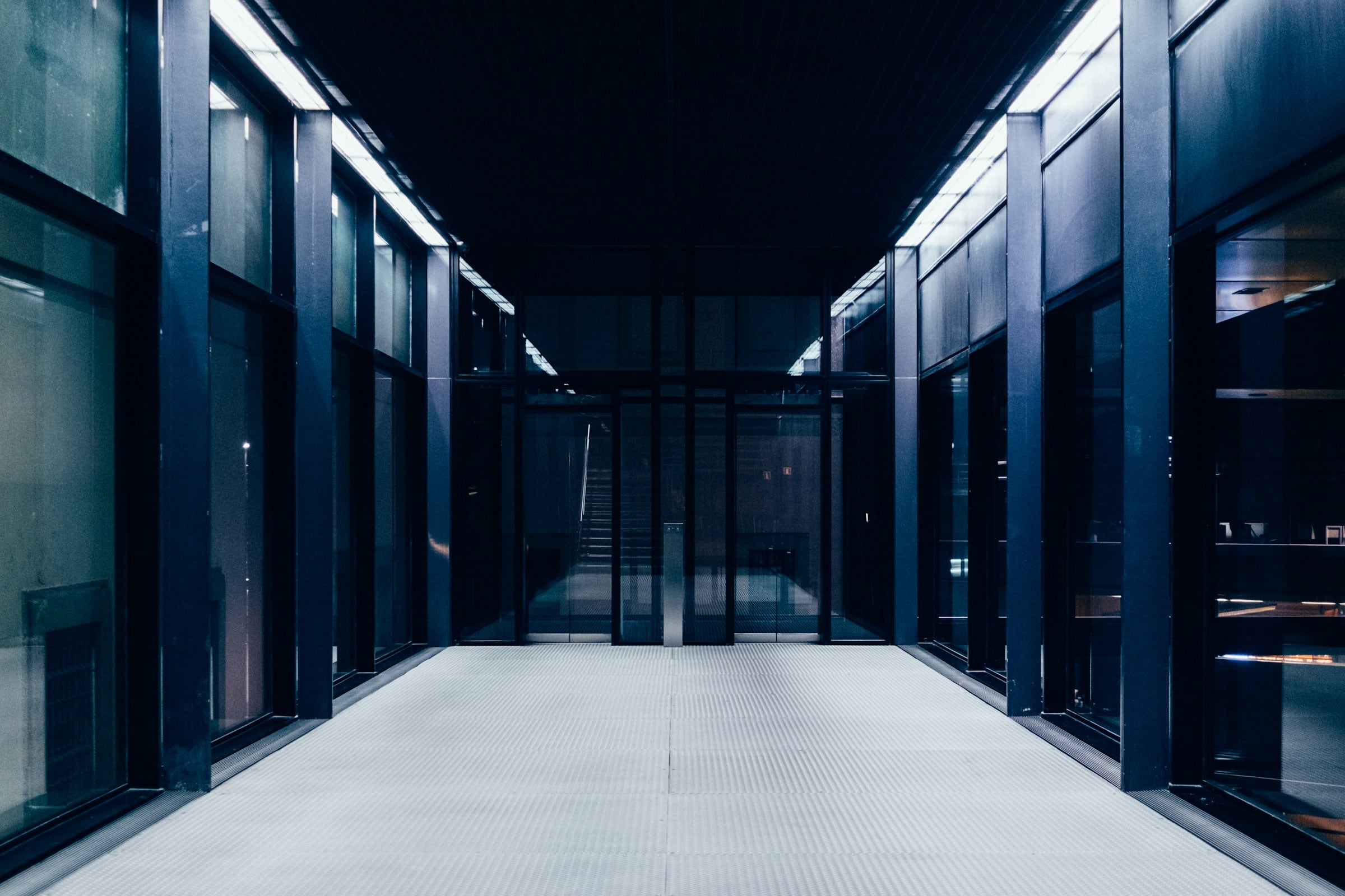 Long data-centre corridor lined with server cabinets behind glass doors