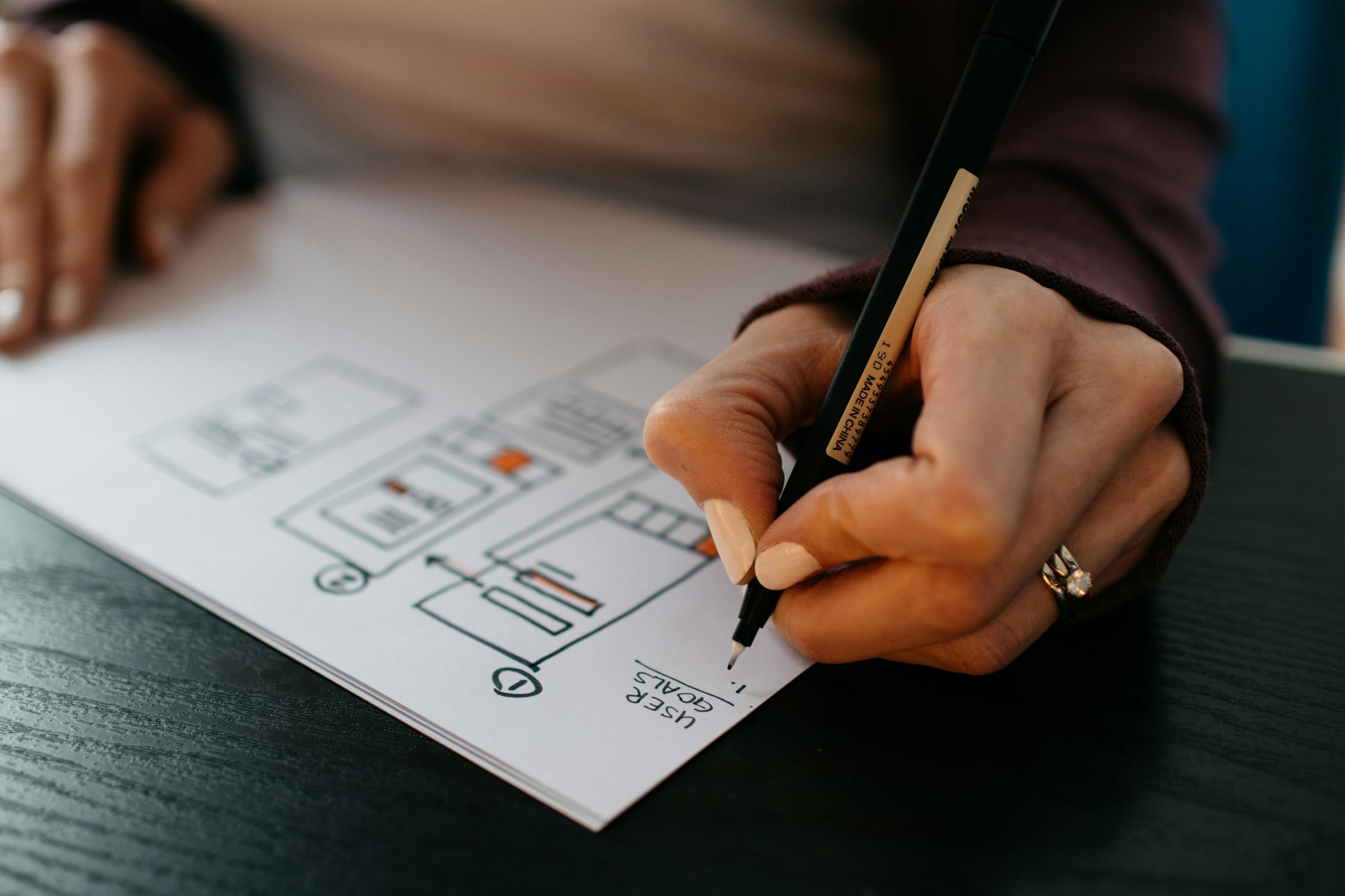 Hands sketching a website wireframe on paper
